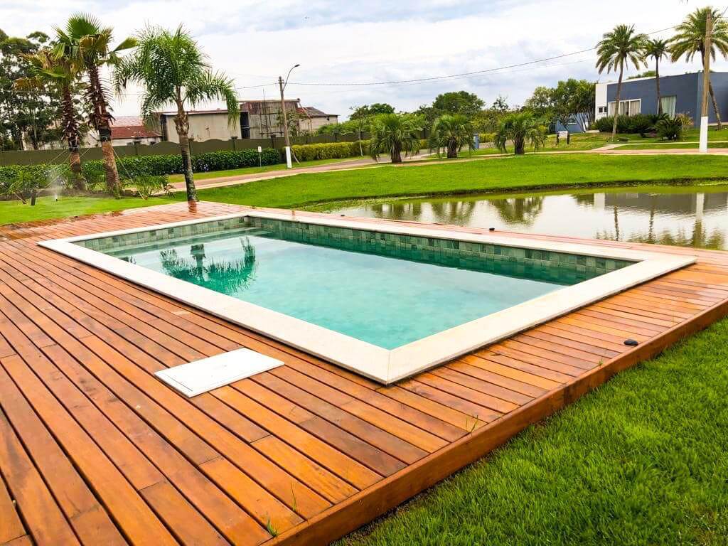 Piscina com deck amplo em área de lazer com lago ao fundo