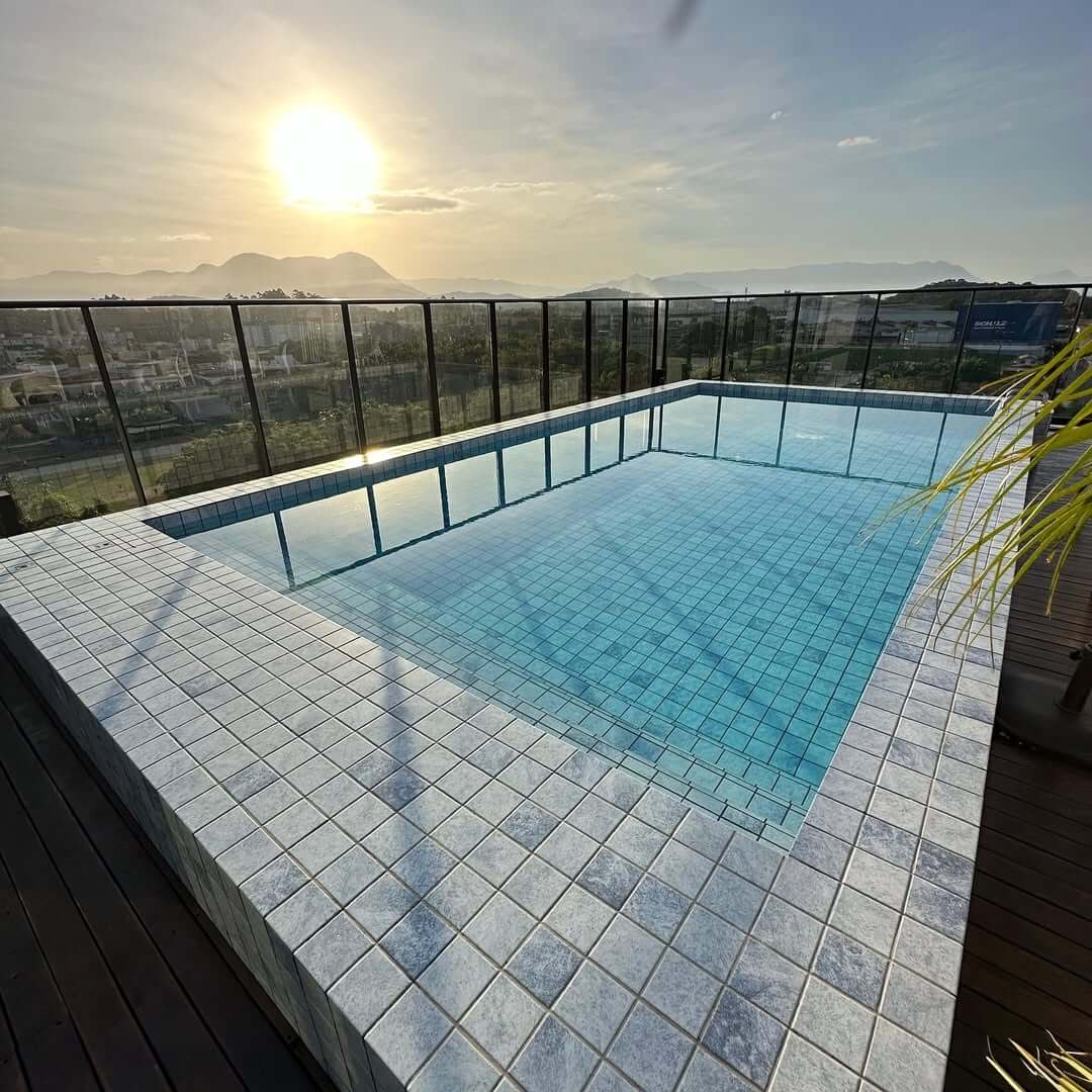 Piscina de alto padrão com borda em porcelanato e vista para a serra ao amanhecer