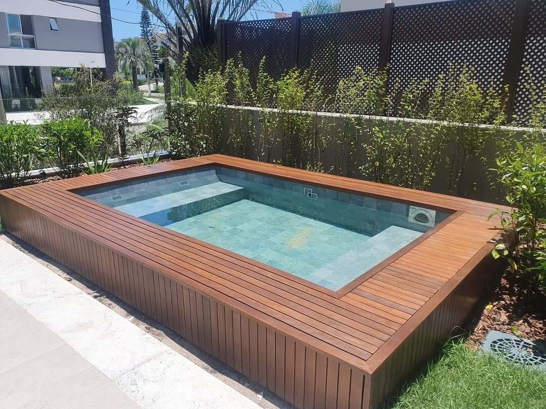 Piscina elevada com deck de madeira e paisagismo