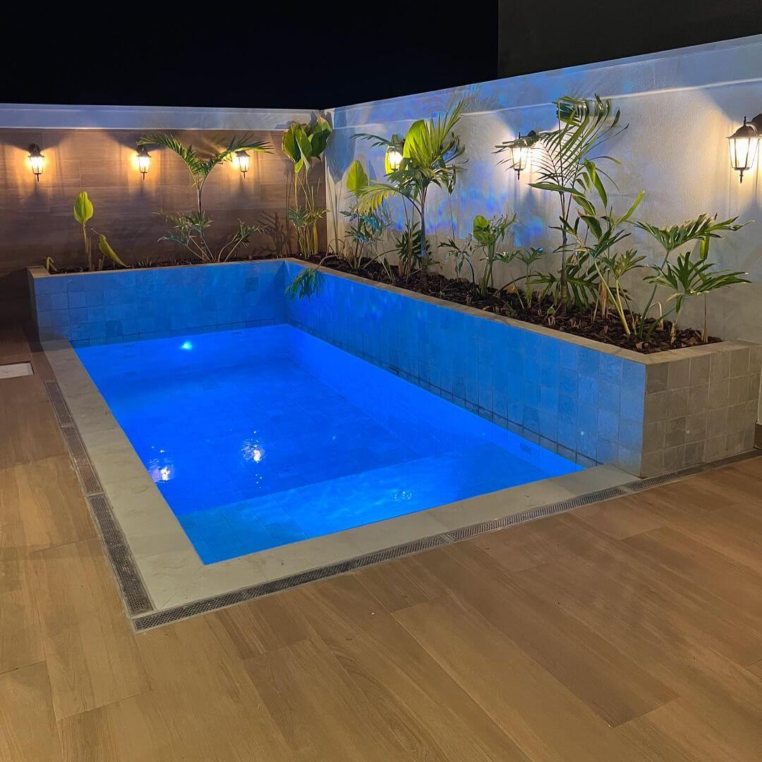 Piscina com iluminação azul e jardim vertical à noite