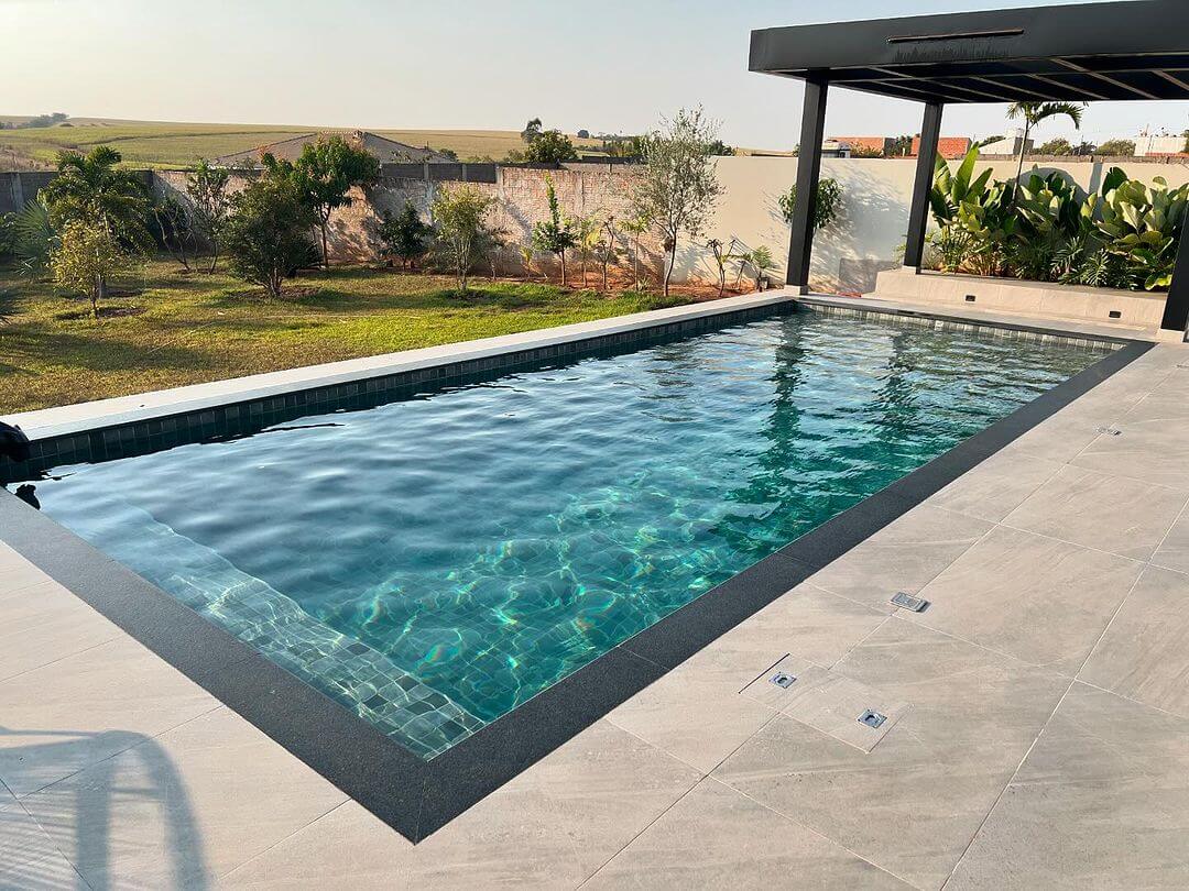 Piscina retangular com borda em granito e pergolado